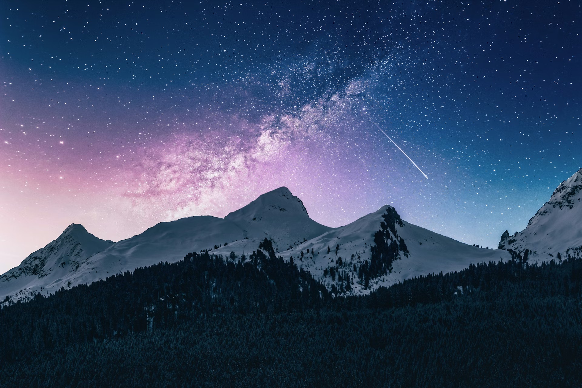 Snow-capped mountains under a starry night sky with the Milky Way and a shooting star
